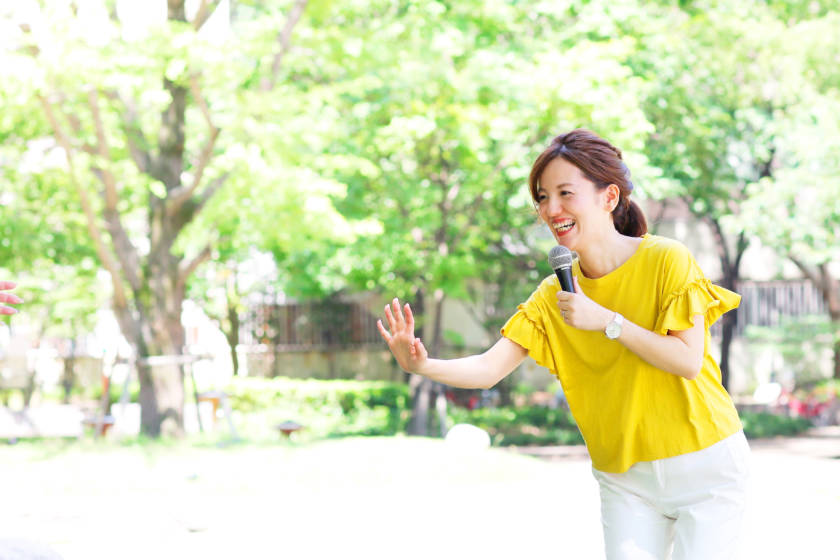写真:片手をあげている笑顔のイベントMC
